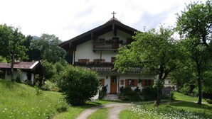 A two-story house with a balcony, surrounded by a garden with a gravel path leading to the entrance. - Apartment- 2 persons, 80sqm, 1 bedroom, balcony, WLAN (Schleching)