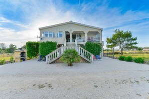 Stunning two-story building with a central entrance and balcony, set amidst a serene lawn and trees.