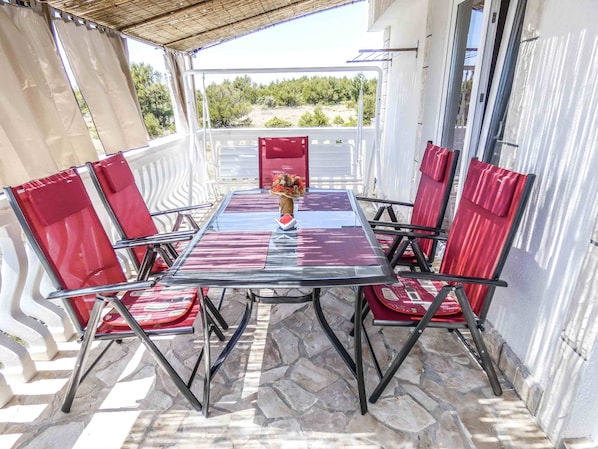 Enjoy dining al fresco under a pergola with a stone floor, surrounded by lush greenery and a scenic view.