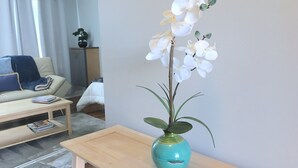 A living room with a sofa, a coffee table, and a vase with white orchids on a wooden side table.