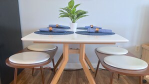 A dining table with four chairs, a potted plant, and a blue placemat.