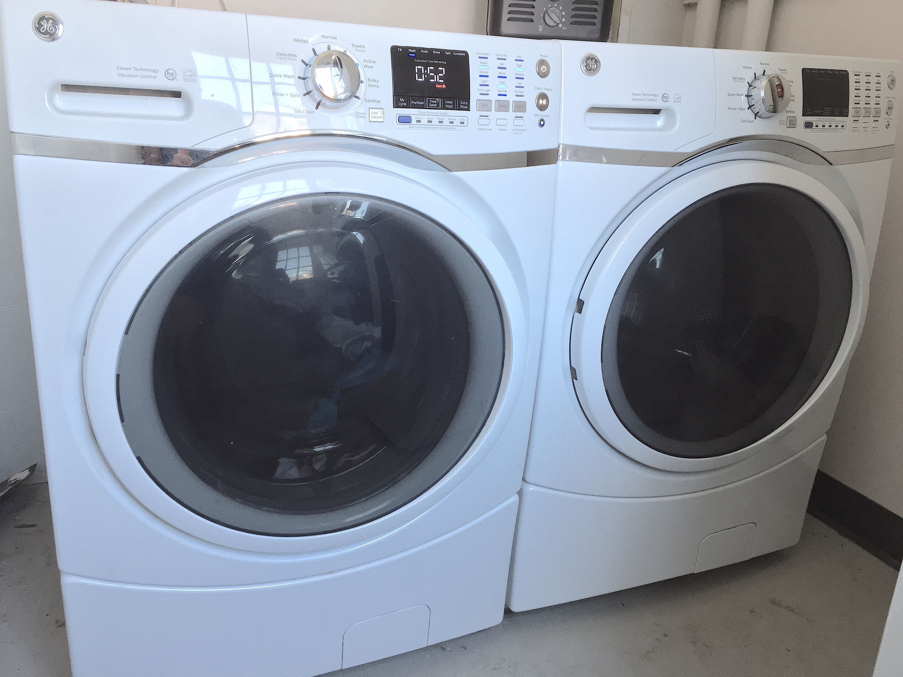 A front view of a front-loading, stacked washer and dryer unit with a digital display and control panel.