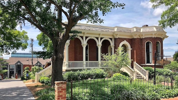 A brick building with a porch and a staircase leading up to the entrance.