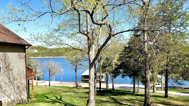 Una propiedad frente al lago con muelle de madera, césped y árboles.