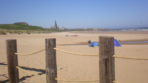 Ein sandiger Strand mit einer Holzzaun und einer Seilsperre.