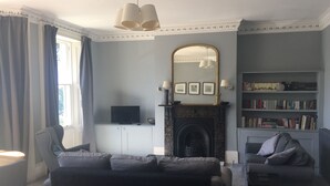 Ein Wohnzimmer mit Kamin, Fernseher, Bücherregal und zwei Sofas.