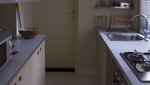 Eine moderne Küche mit weißen Schränken, einer Spüle aus Edelstahl und einem Gasherd.