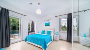 A spacious bedroom with a large bed, a bedside table, a nightstand, and a window with curtains.
