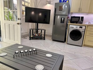 Une cuisine moderne équipée d’un téléviseur à écran plat, d’appareils électroménagers en acier inoxydable et d’un coin repas avec une table dressée pour quatre personnes.
