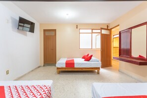A bedroom with a bed, a TV, a wooden door, and a window. - OYO Hotel Emperador, Oaxaca (Oaxaca)