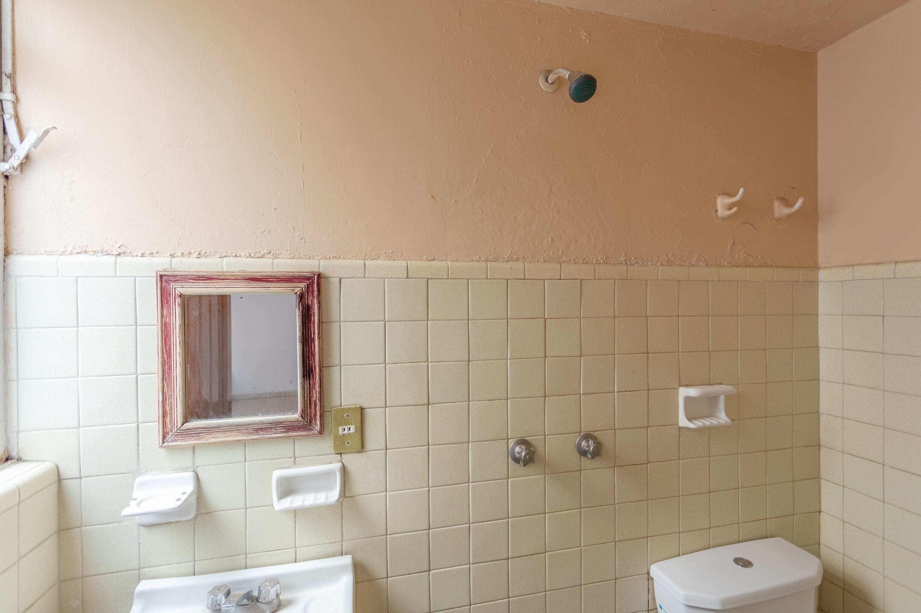 A bathroom with a tiled wall, a sink, a toilet, and a mirror.