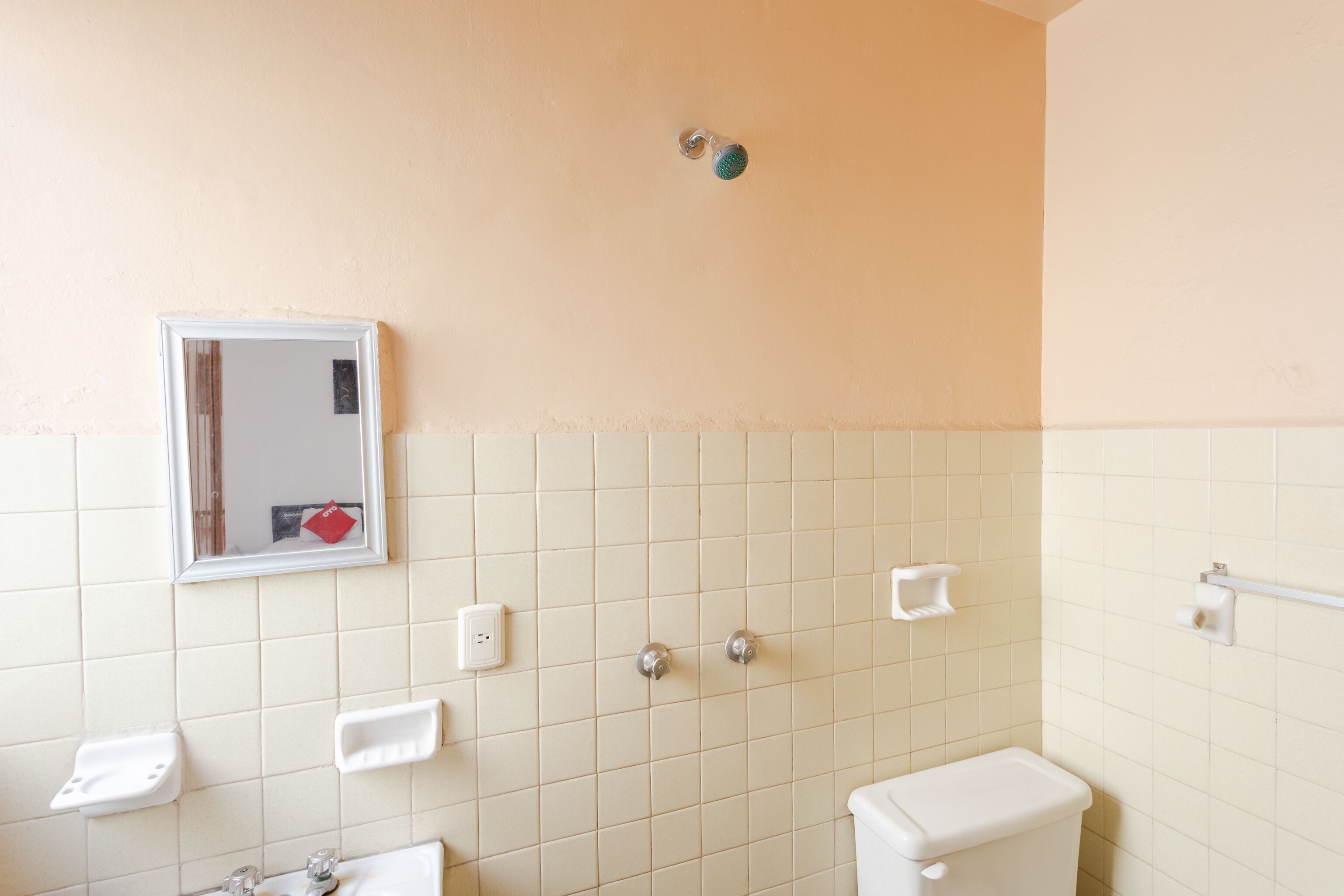 Un baño con inodoro, lavabo, espejo y paredes de azulejos.