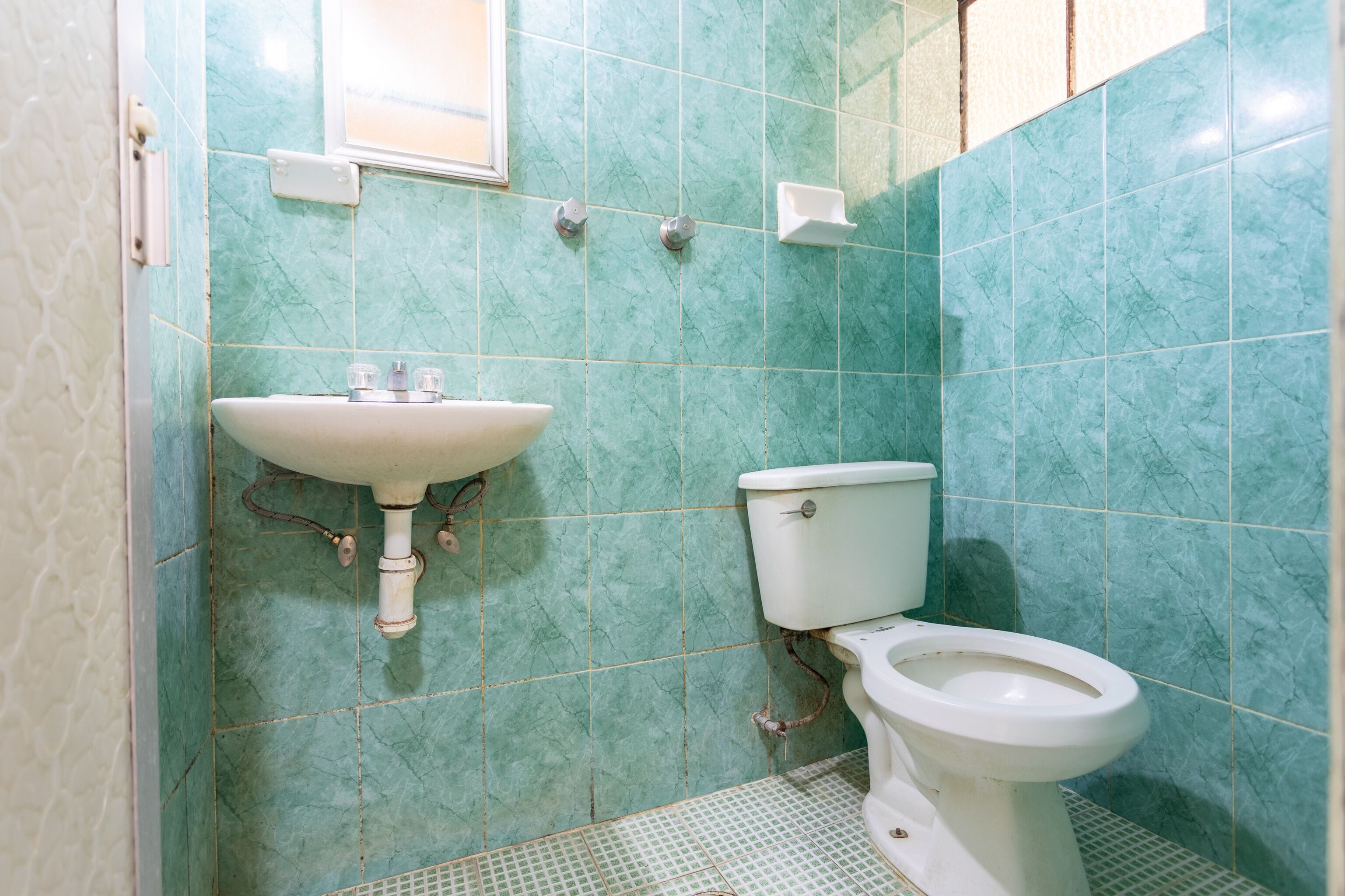 Et badeværelse med vask, toilet og fliserede vægge.