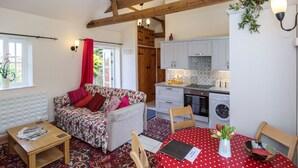 A cozy room with a floral sofa, a small wooden table, a polka dot tablecloth, and a red chair.