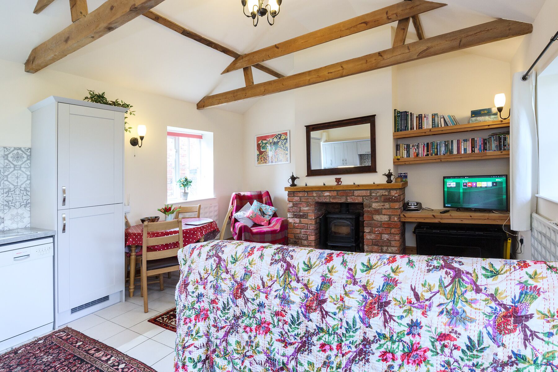 A cozy living room with a fireplace, a television, and a bookshelf.