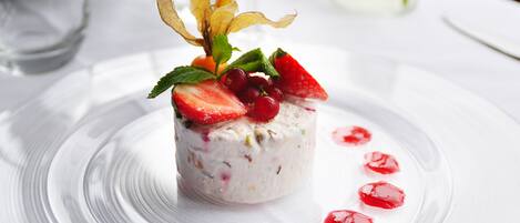 A dessert with strawberries and red berries on a clear glass plate.