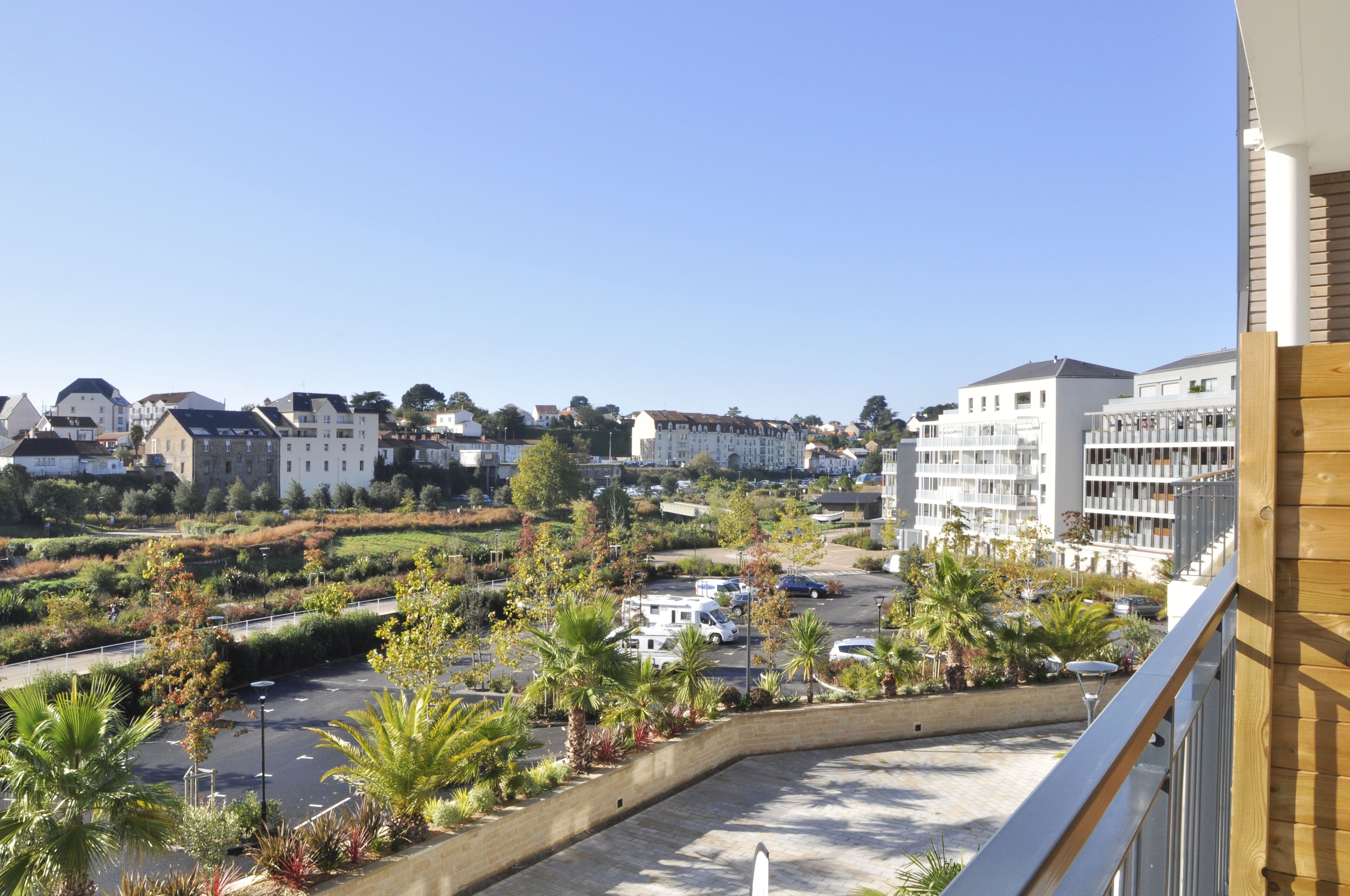 A residential area with a parking lot, palm trees, and buildings.