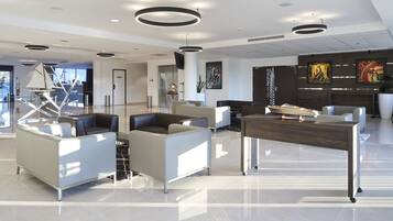 Eine moderne Lobby mit zeitgemäßer Einrichtung, einem Empfangsbereich und Kunstwerken an den Wänden.
