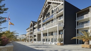 A modern hotel with multiple balconies, a flag, and a clear sky. - Westotel Pornic (Pornic)