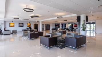 A modern lobby with a central seating area, a reception desk, and a large window providing a view of the outdoors.