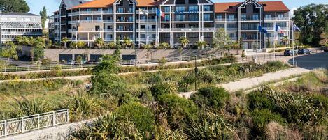 A multi-story hotel with balconies, a parking area, and a landscaped garden.