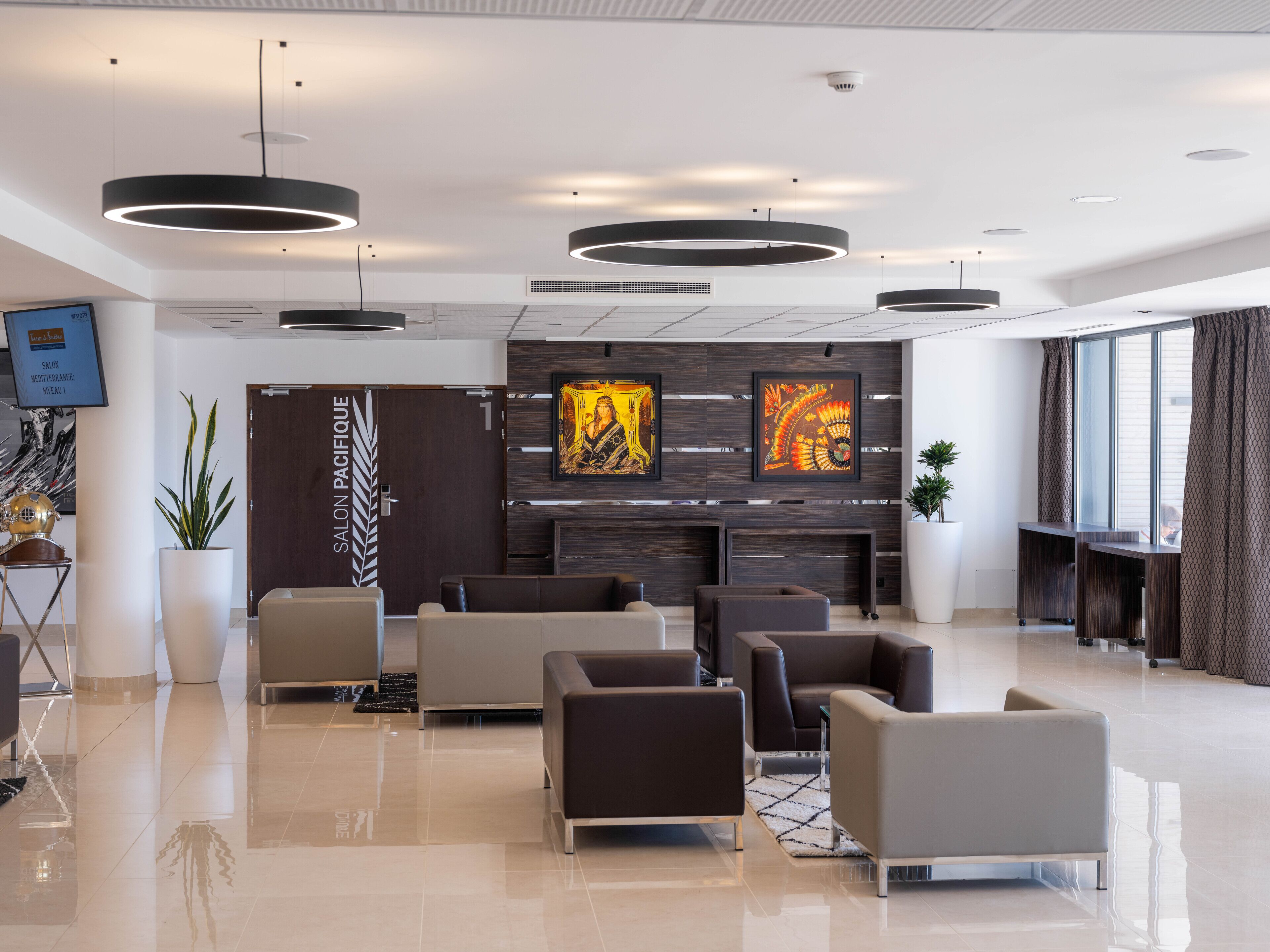 A modern lobby with a reception desk, seating area, and artwork on the walls.