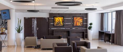 A modern lobby with a reception desk, seating area, and artwork on the walls.