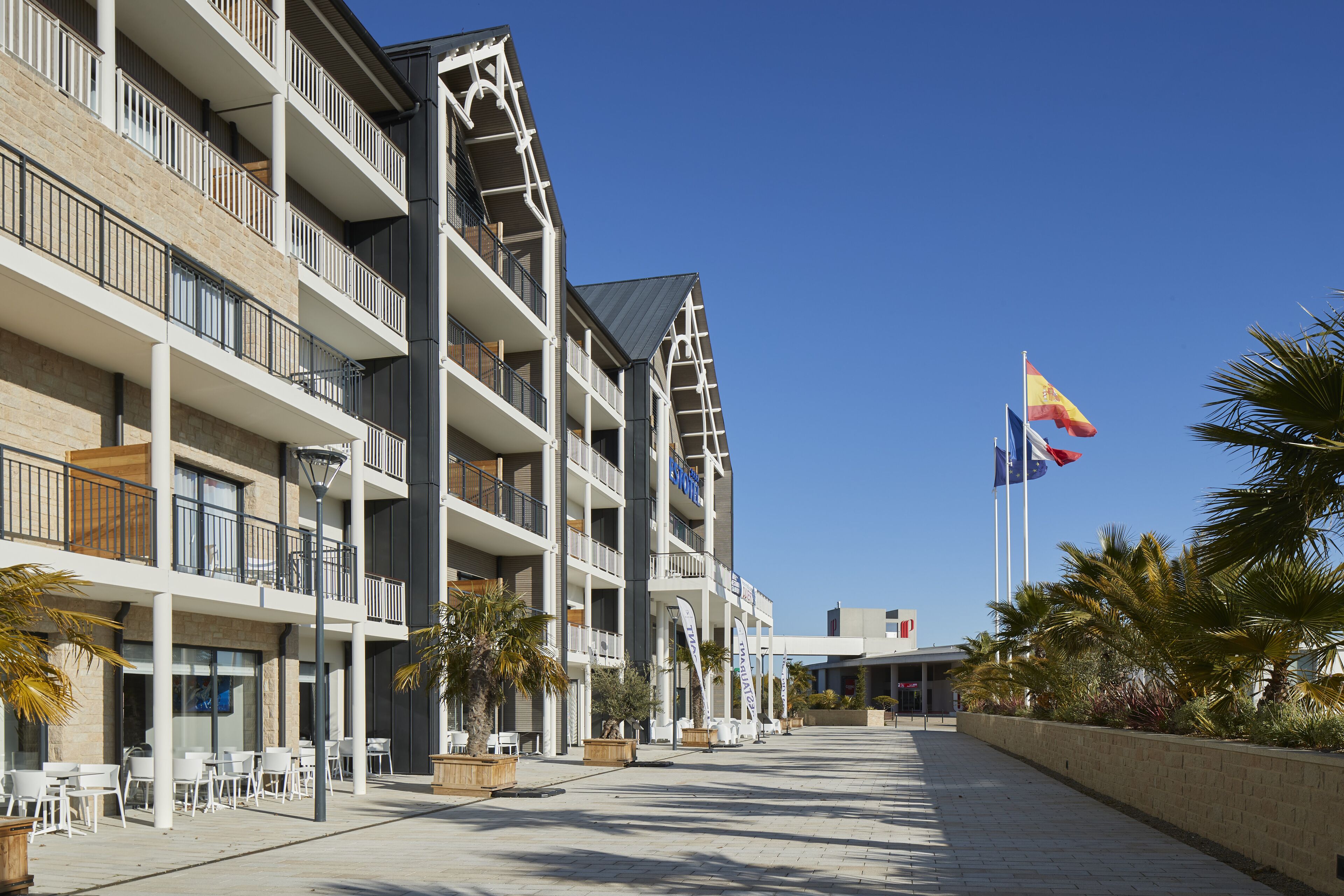 Hotel de diversos pisos amb balcons, terrasses exteriors i palmeres.