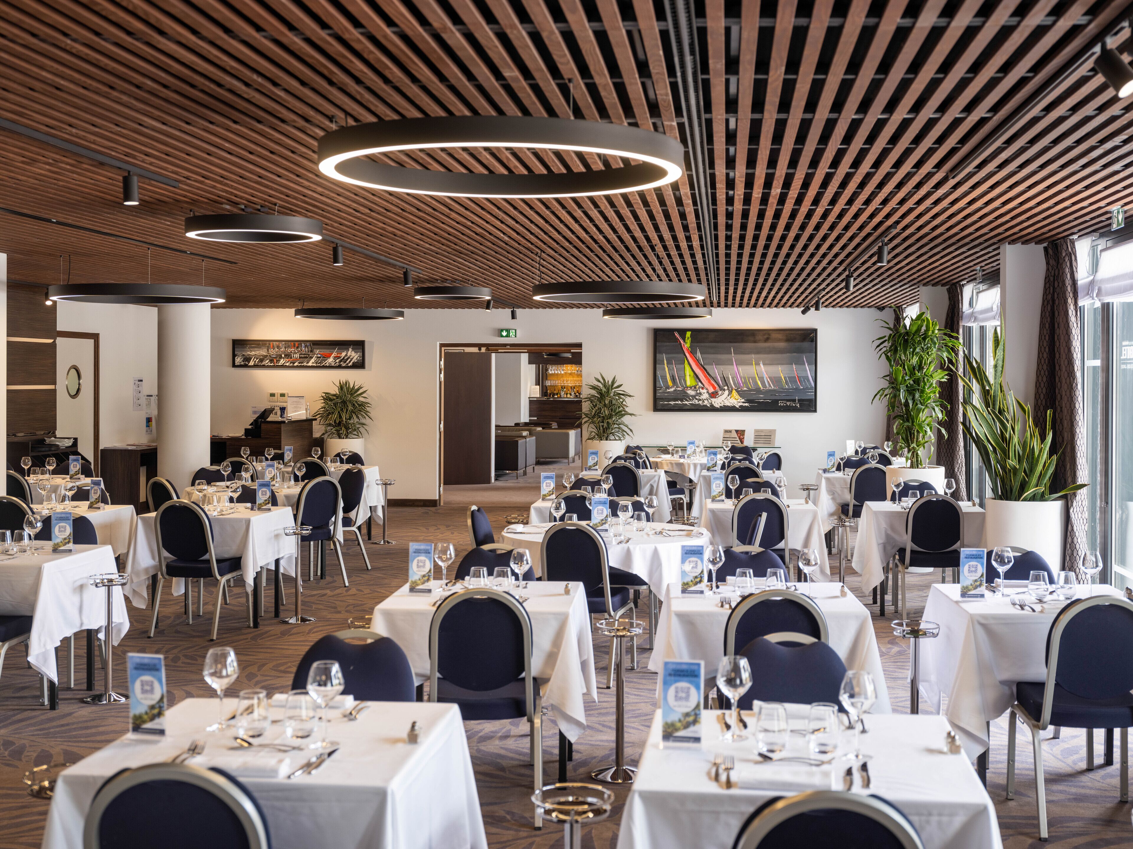 A spacious dining area with multiple tables, chairs, and modern lighting fixtures.