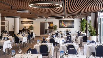 A spacious dining area with multiple tables, chairs, and modern lighting fixtures.