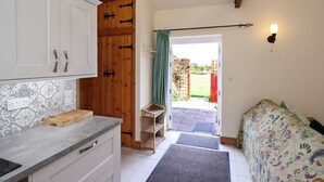 A kitchen with white cabinets, a wooden door, and a countertop with a cutting board. -  YORK single storey cottage ,gardens & open views.Thicket Priory & Derwent Ings. (Thorganby, York)