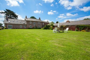 A large, spacious lawn with a traditional brick house in the background.