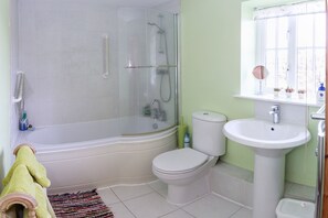 A bathroom with a glass-enclosed shower, a white toilet, a pedestal sink, and a window with a view.