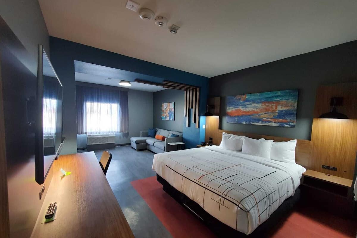 Een moderne hotelkamer met een groot bed, een bureau, een bank en een schilderij aan de muur.