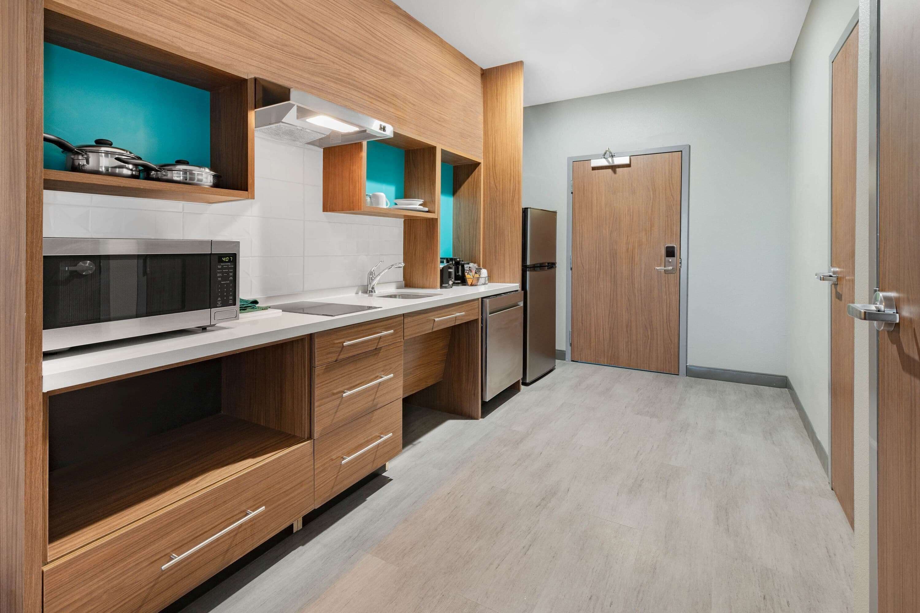 A modern kitchen with wooden cabinets, a microwave, a refrigerator, and a sink.