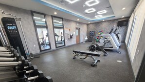 Une salle de sport équipée de tapis de course, de vélos de spinning et de matériel de musculation.