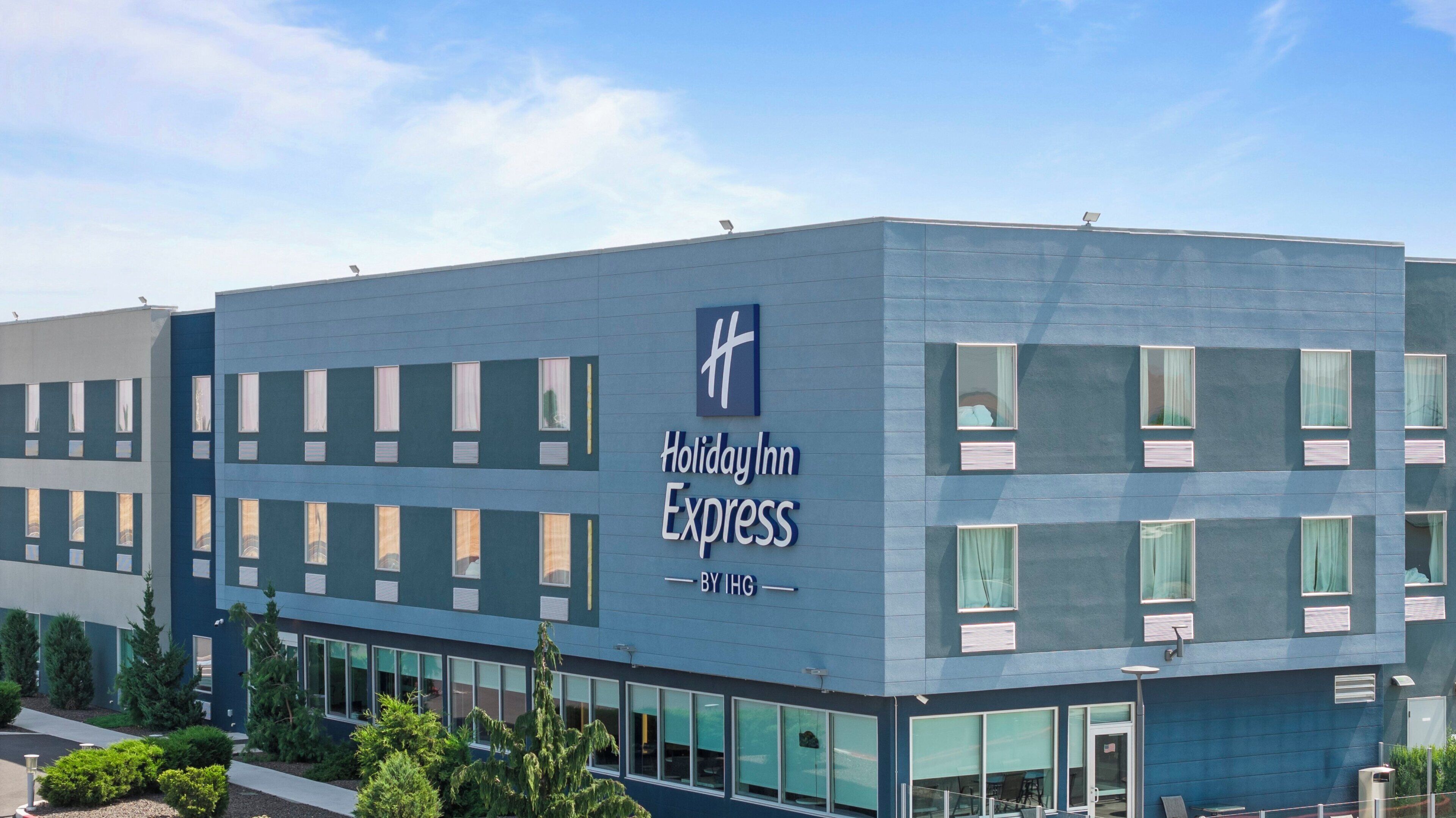 A Holiday Inn Express building with a modern design, large windows, and a clear sky.