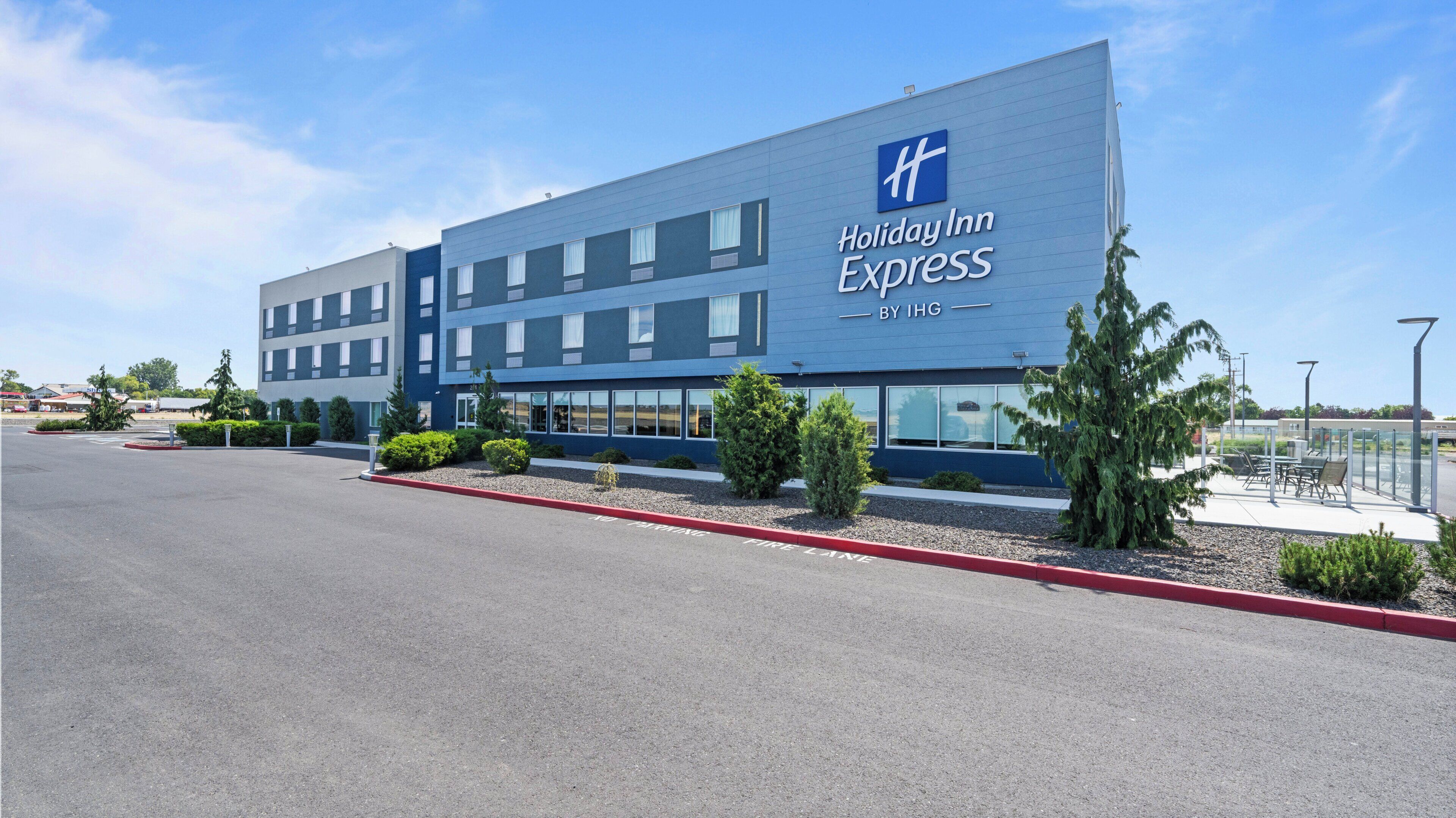 A Holiday Inn Express hotel with a modern design, featuring a large sign, multiple windows, and a parking lot.