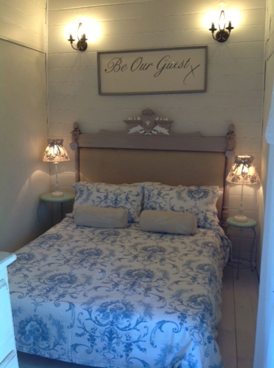 Une chambre à coucher avec un lit, deux tables de chevet et un panneau fixé au mur.