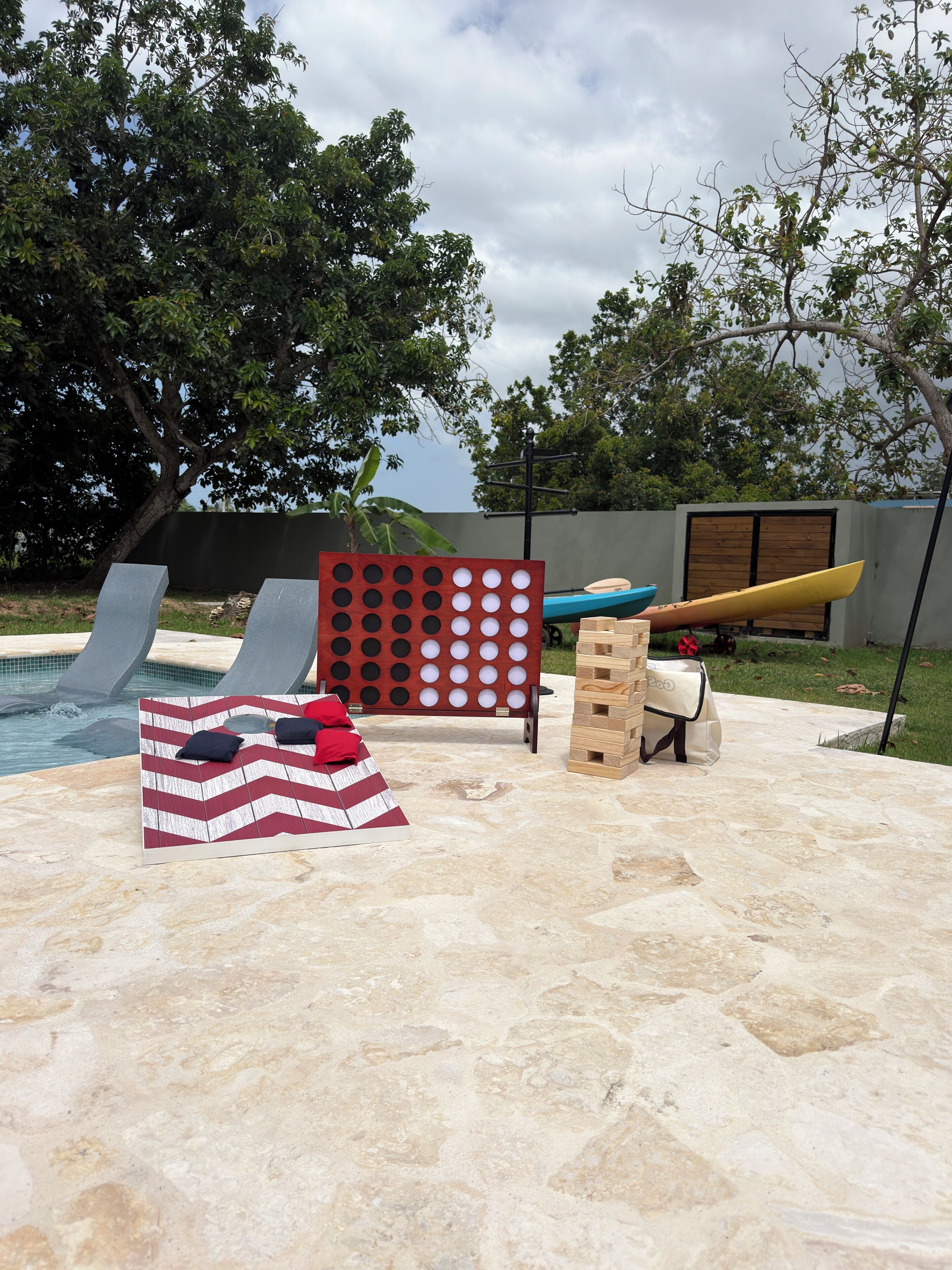 A poolside area with lounge chairs, a paddleboard, and a board game setup.