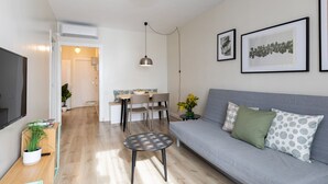 A modern living room with a grey sofa, a round coffee table, and a dining area with a table and chairs. - Casa Cosi - Sants Barcelona (Barcelona)
