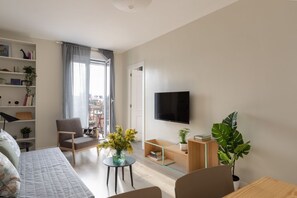Ein modernes Wohnzimmer mit einer Couch, einem Sessel, einem Fernseher und einem Bücherregal.