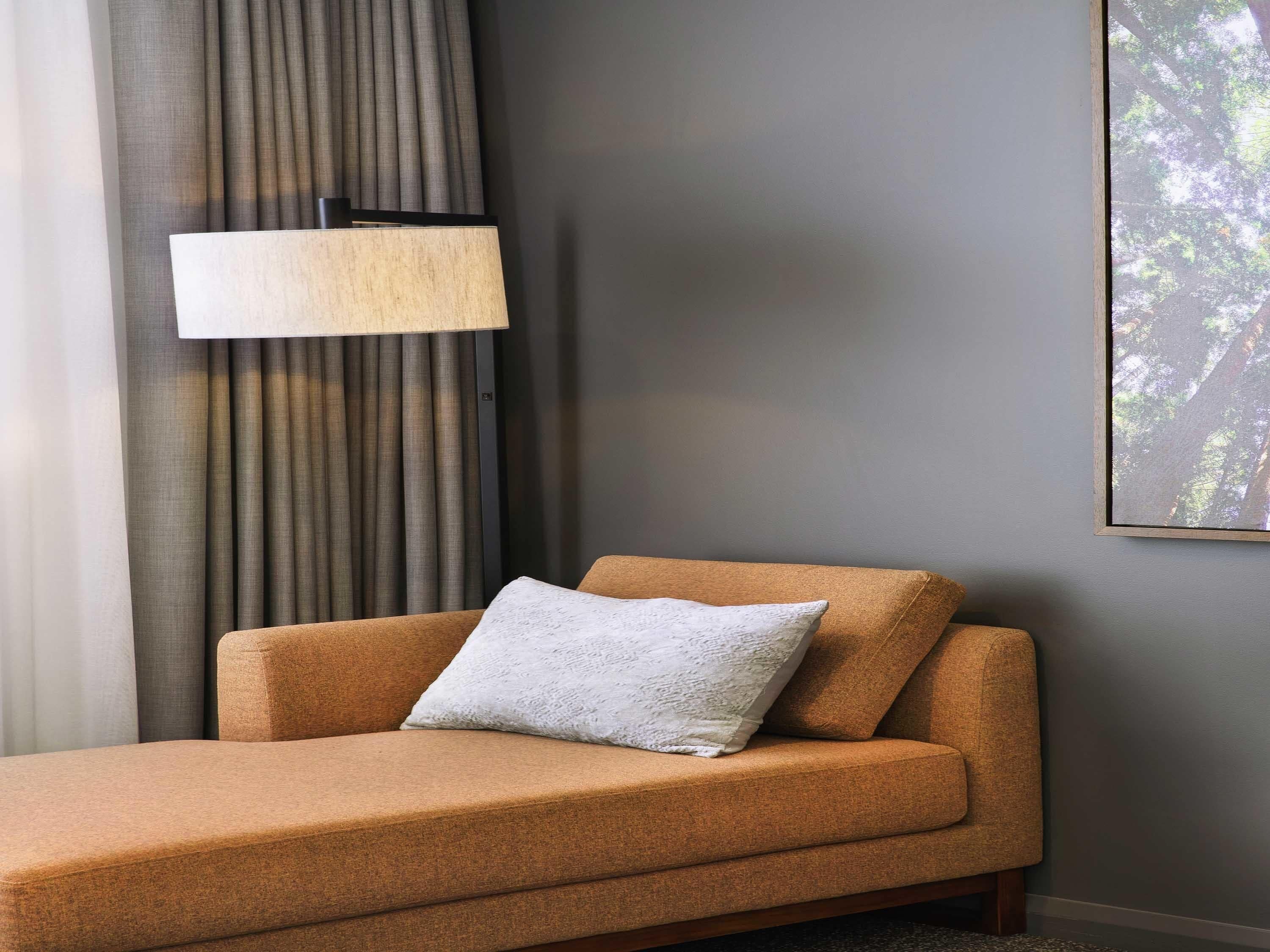 Una habitación moderna con un sofá, una lámpara y un cuadro en la pared.