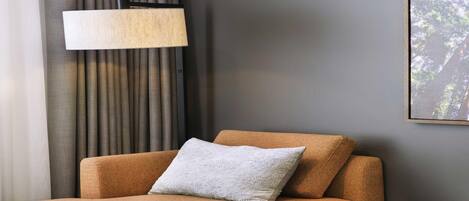 Una habitación moderna con un sofá, una lámpara y un cuadro en la pared.