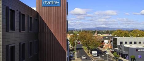 Un edificio con un letrero que dice 'mantra', un estacionamiento y una vista de la calle con vehículos.