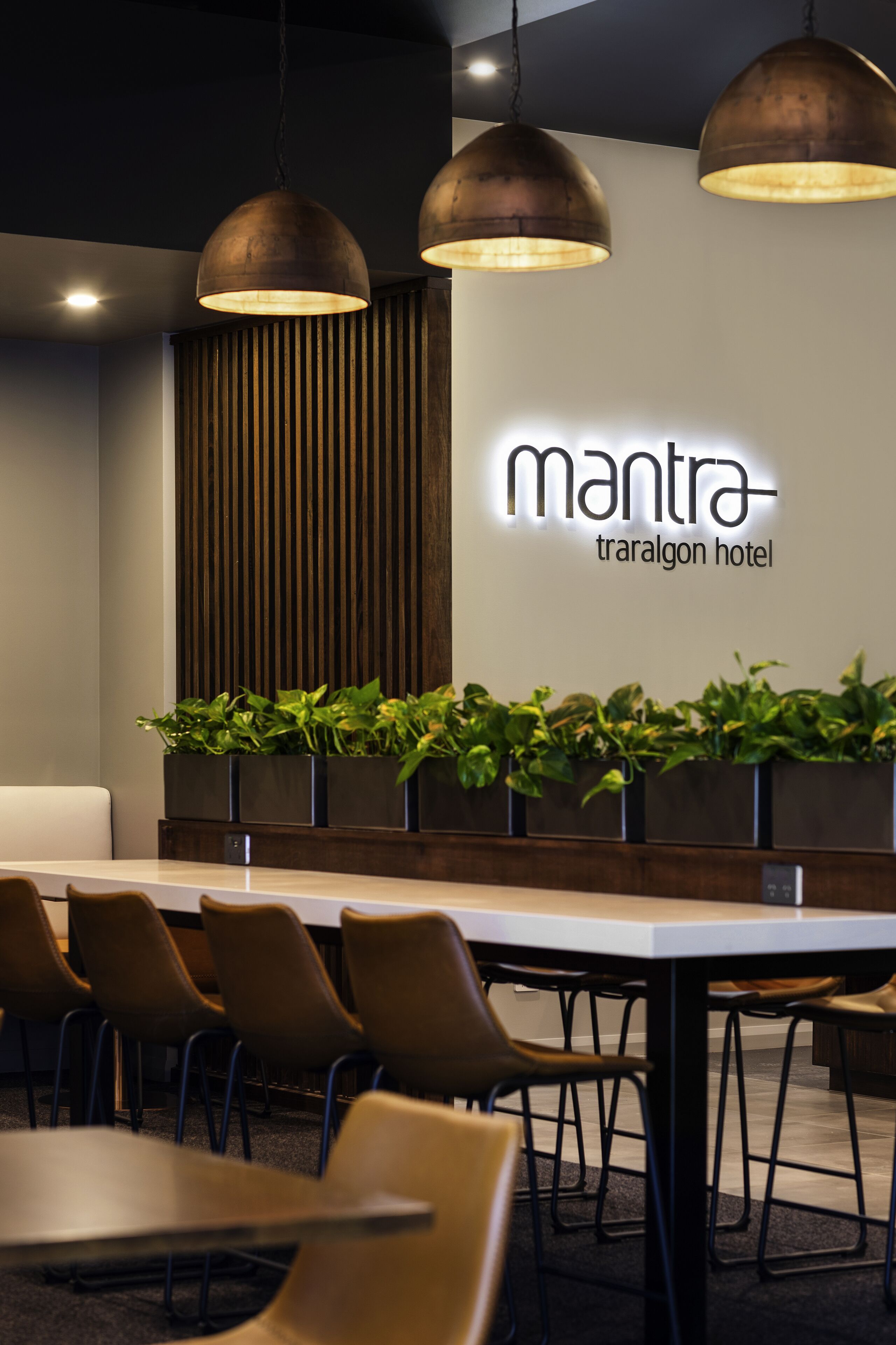 A modern hotel lobby with a reception desk, seating area, and pendant lighting.