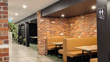 A restaurant with brick walls, leather booths, and a sign indicating restrooms.
