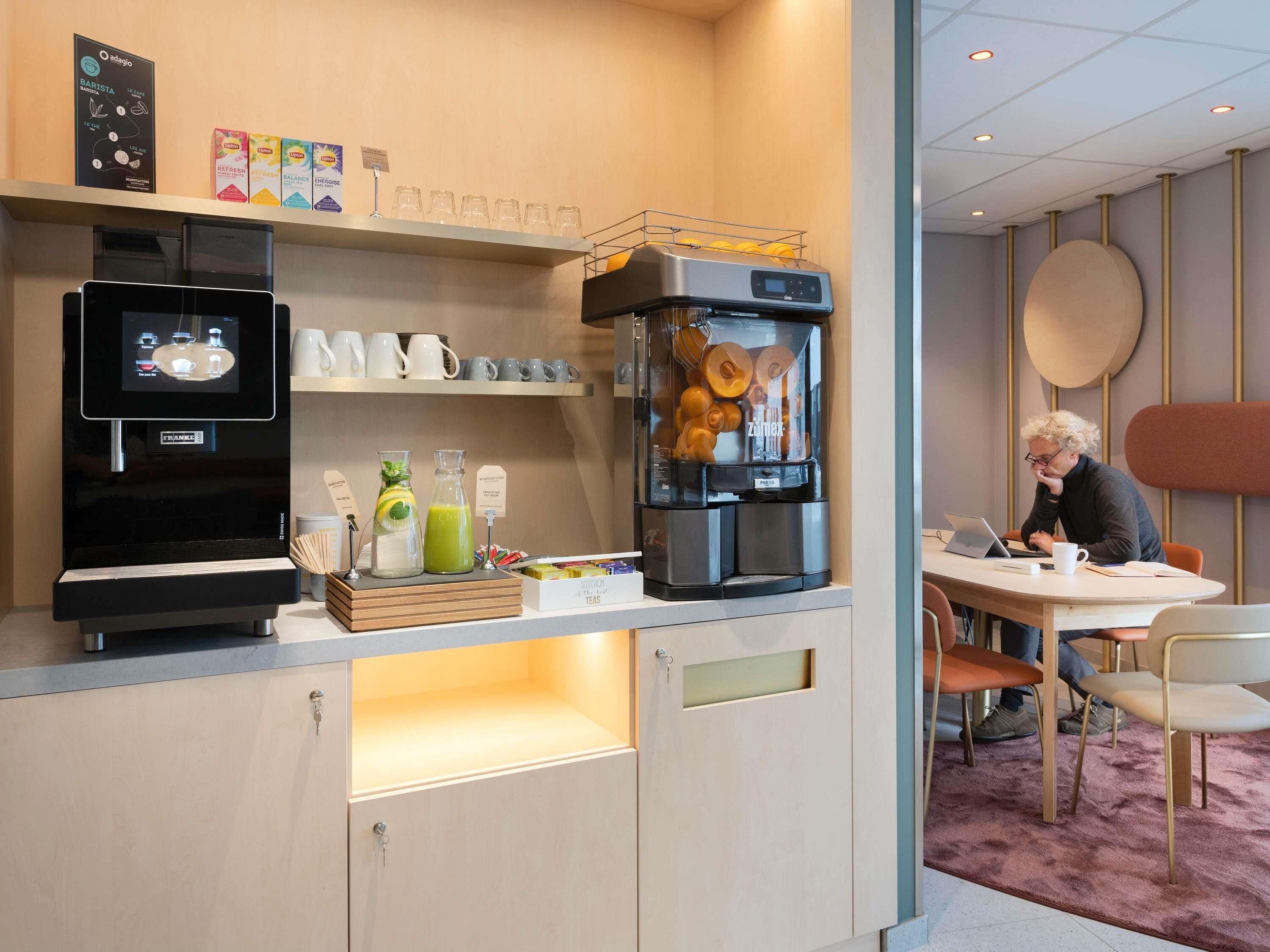 Una kitchenette moderna con cafetera, set de té y refrigerador.