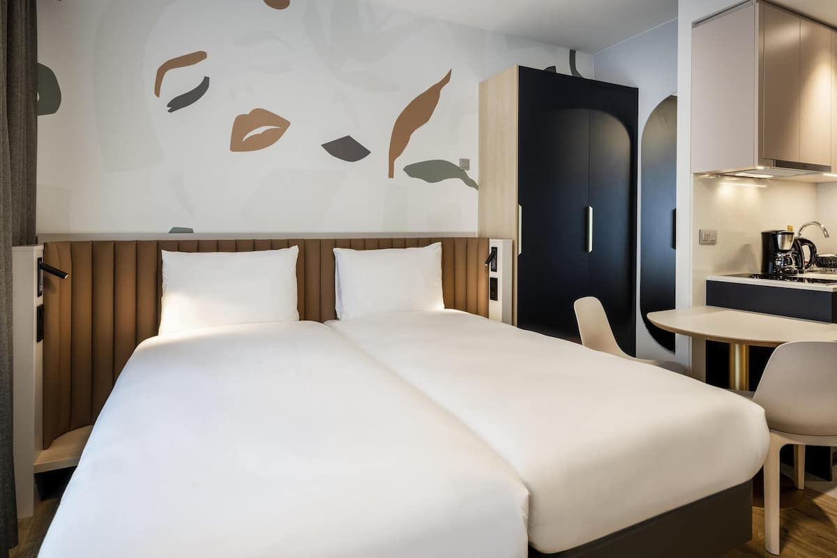 A hotel room with a large bed, a desk, and a kitchenette.
