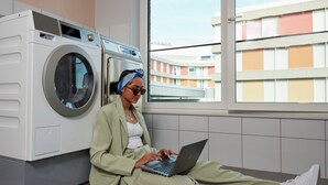 A person sitting on the floor next to a washing machine, using a laptop. - Aparthotel Adagio Access Brussels Delta (Brussels)